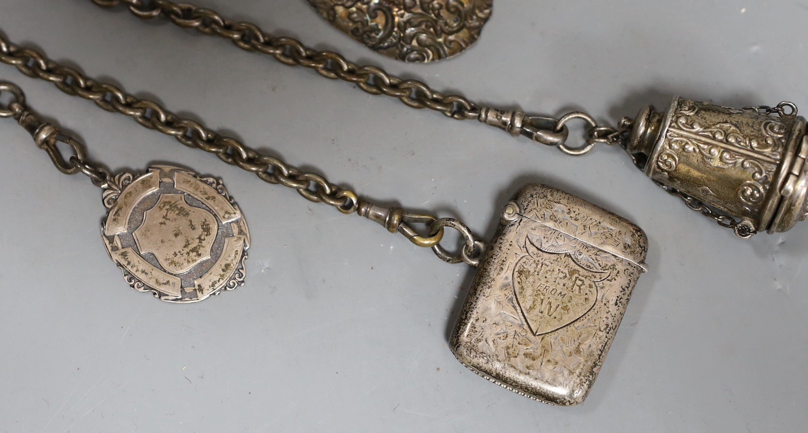 A 19th century plated five chain chatelaine, with a thimble holder, a silver Vesta and a medallion, a note book and two oval metal panels